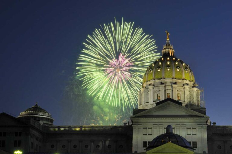 The PA capitol at night with green fireworks going off next to the dome.